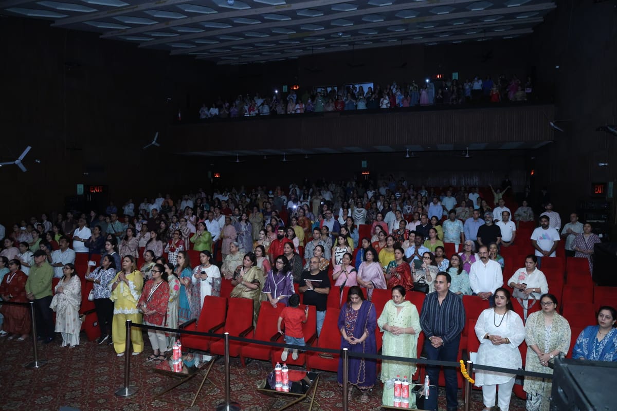 The whole hall standing, the balcony packed above rows of red seats.